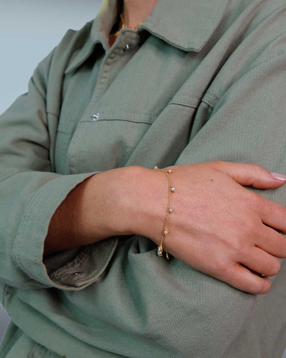 Close-up of gold bracelet featuring graduated pearl detailing