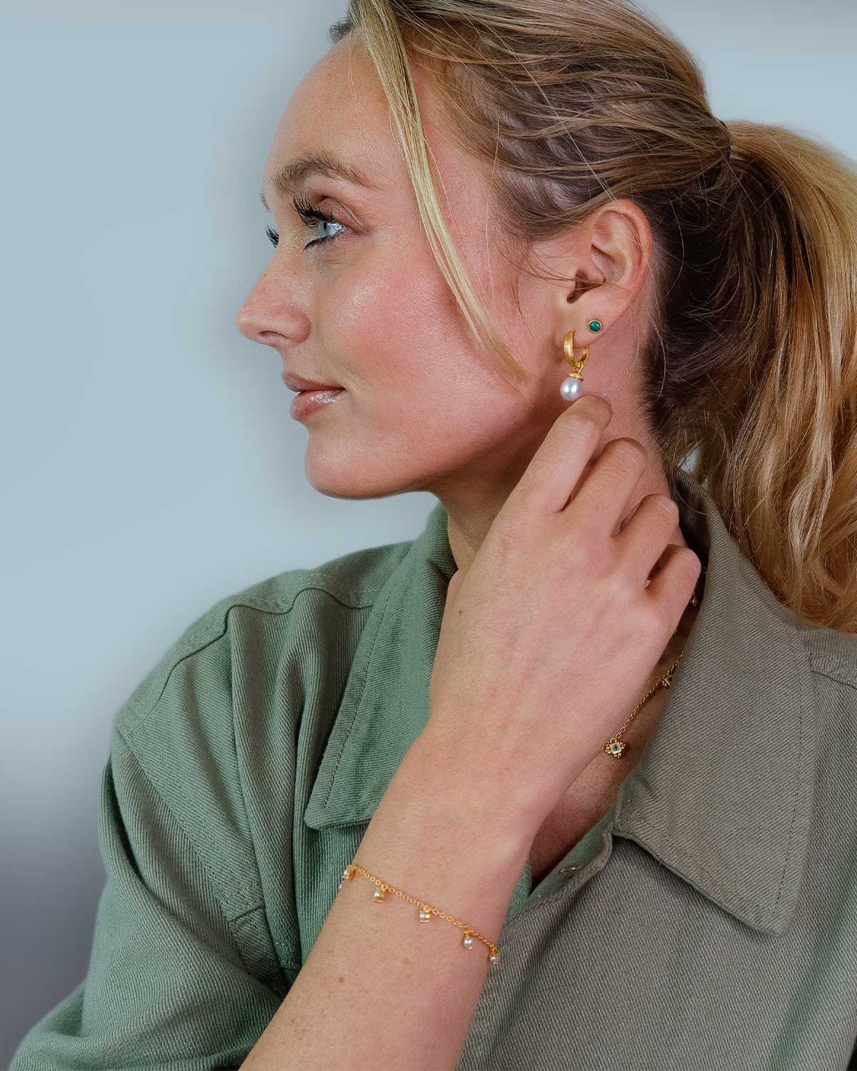 Model wearing a gold bracelet with graduated pearl design