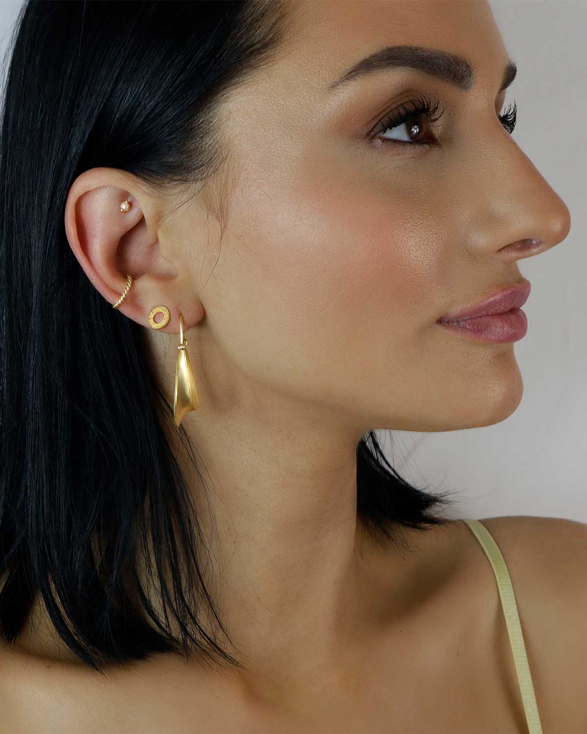 Model wearing twisted gold hoop earrings with a polished finish