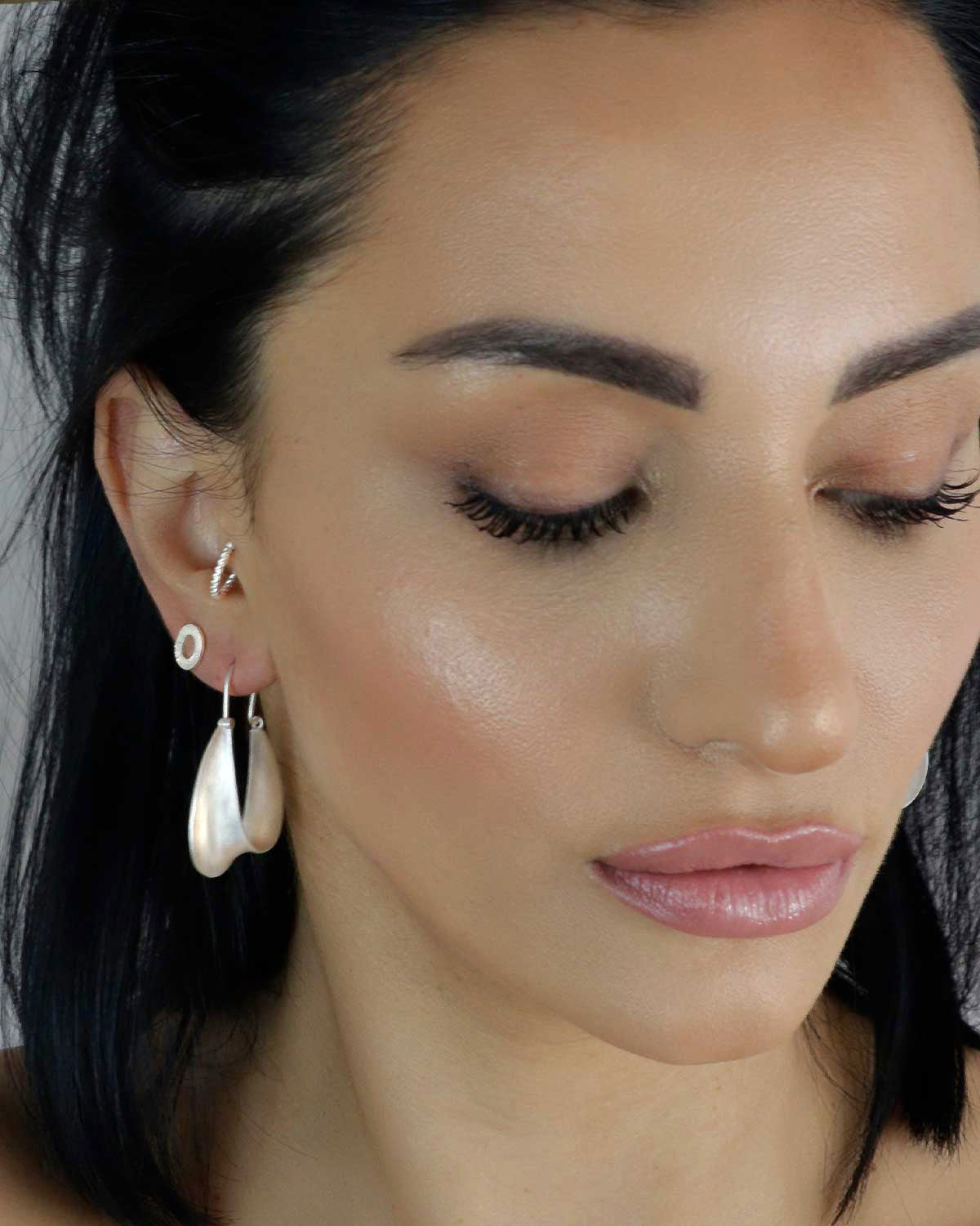 Close-up of twisted silver hoop earrings with handcrafted detailing