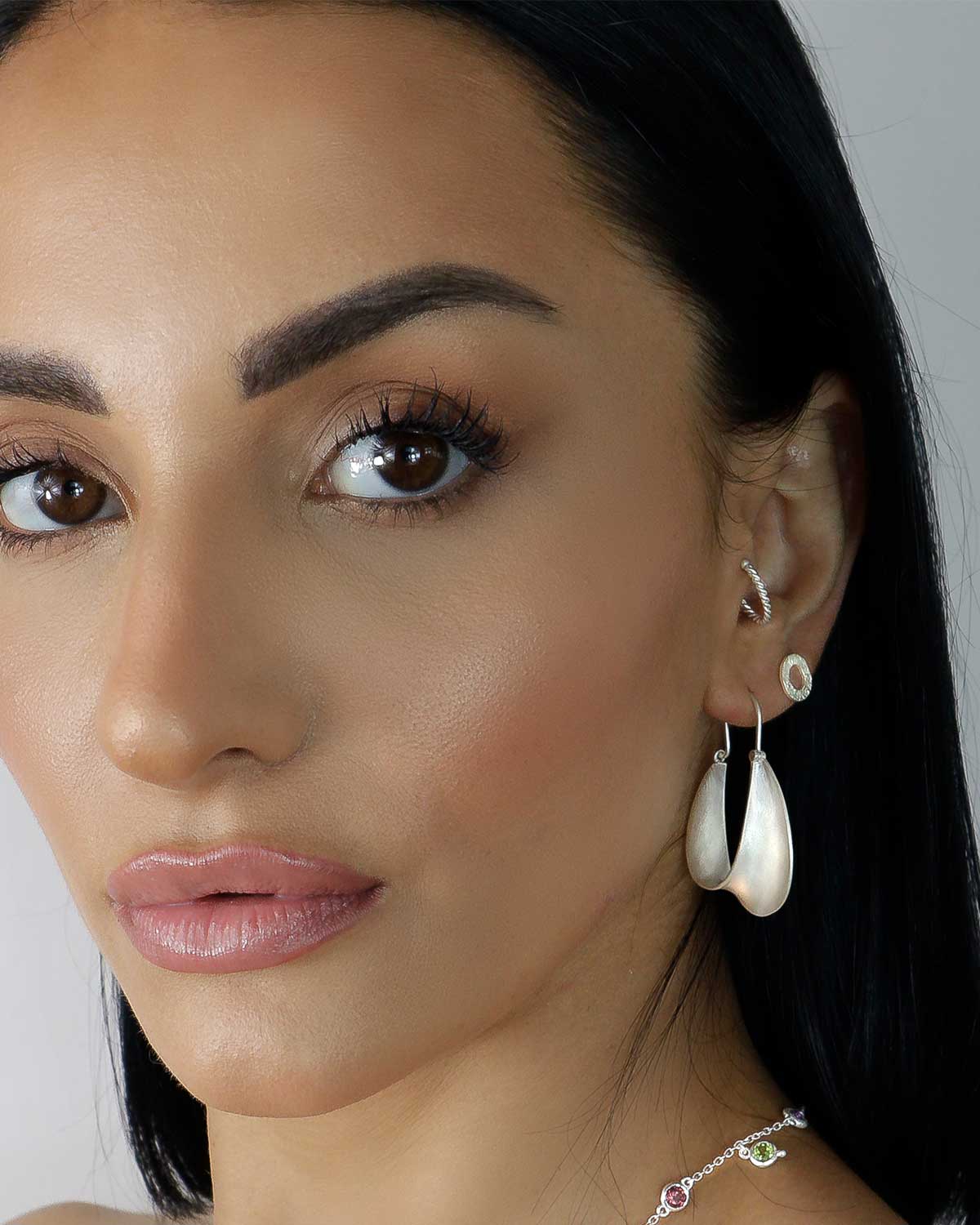 Model wearing twisted silver hoop earrings with a polished finish