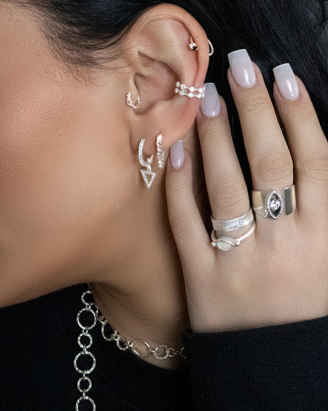 Model wearing chunky silver ring with symbolic eye design