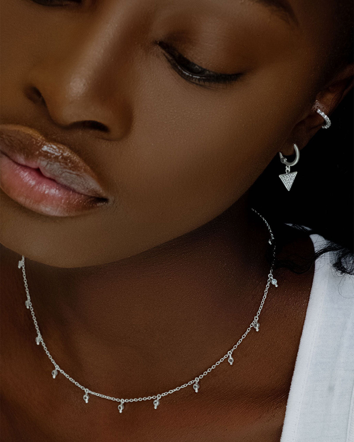 Model wearing mini hoop earrings with crystal triangle charms