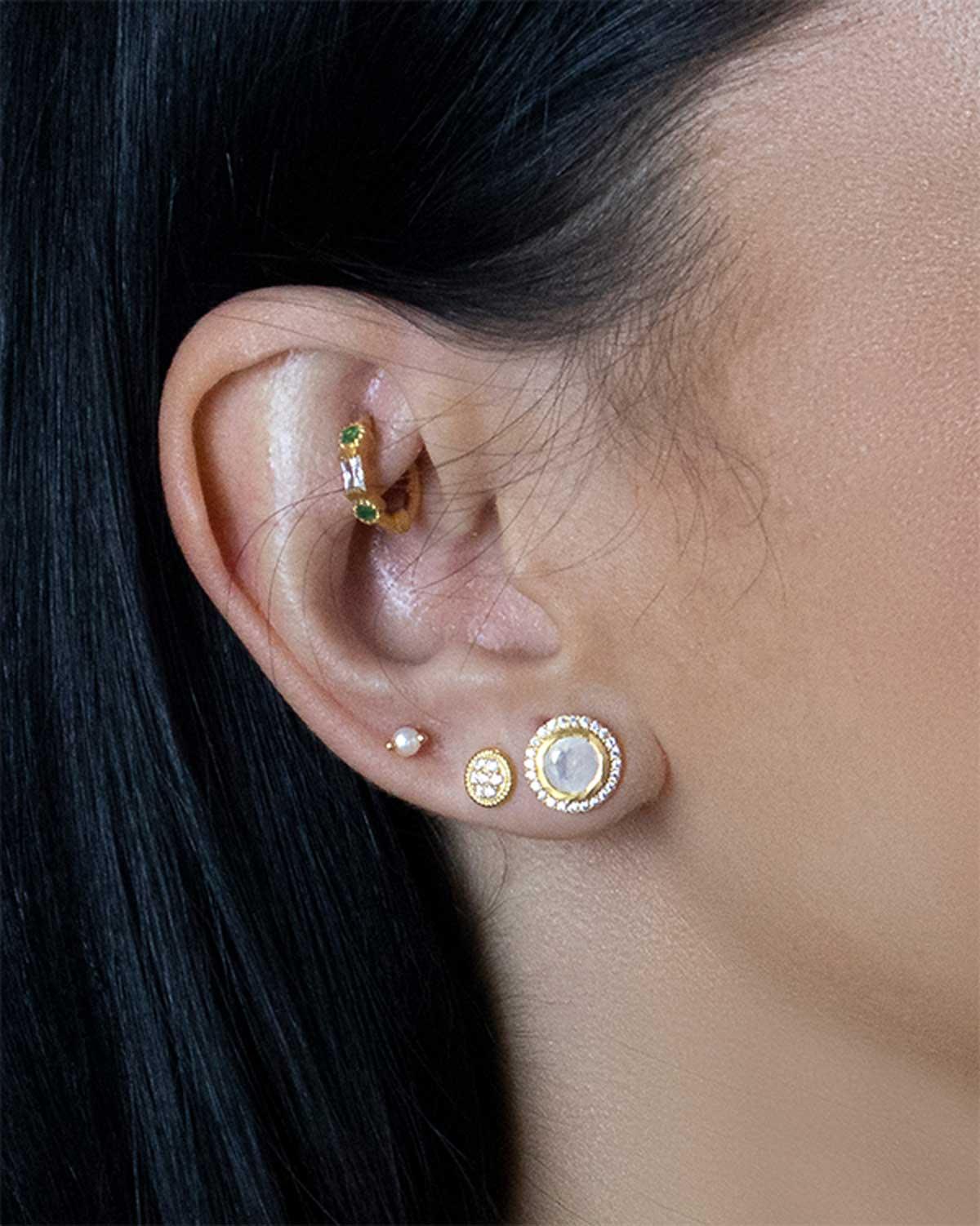 Close-up of small gold stud earrings with a sparkly circular design