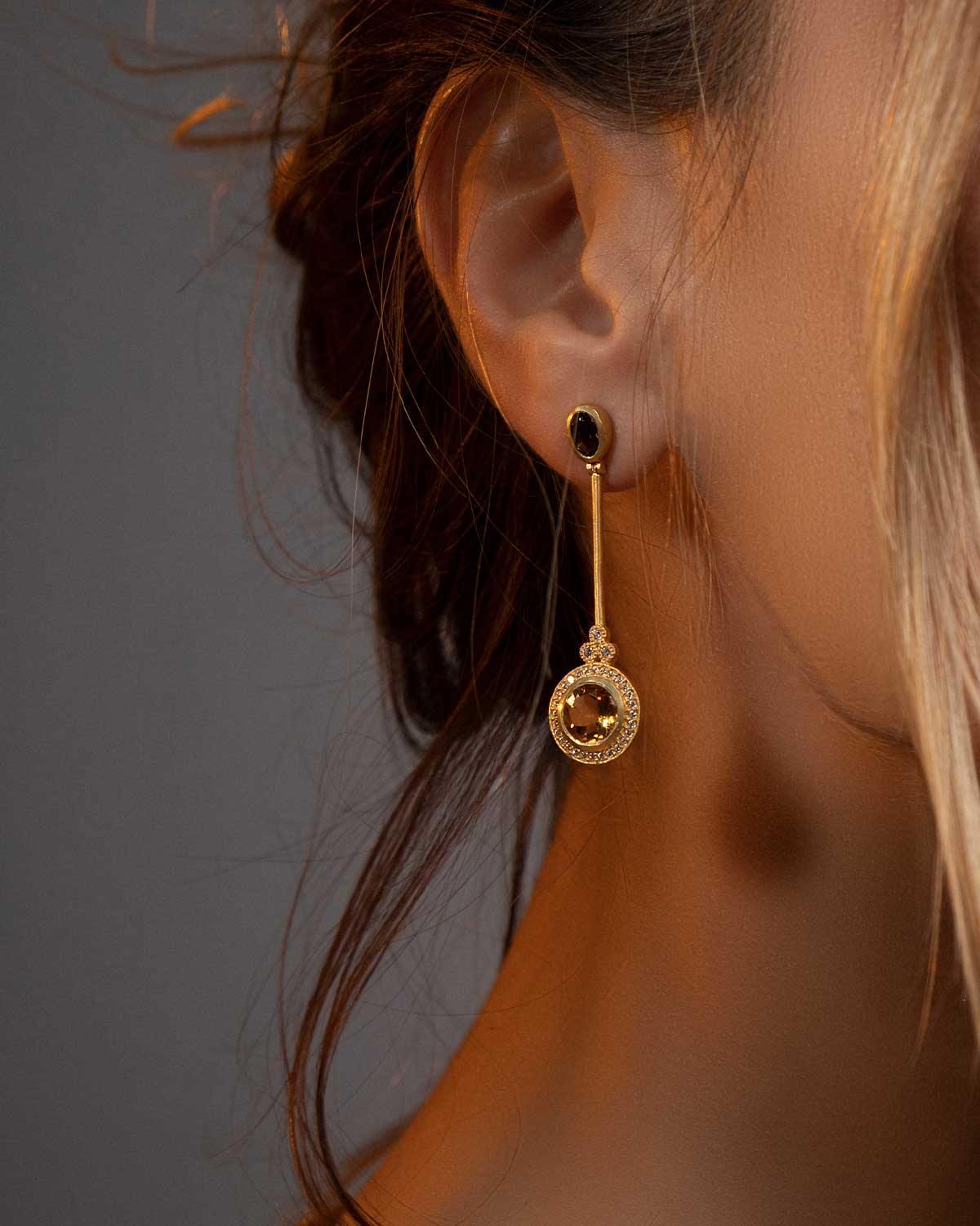 Model wearing flowing gold earrings with citrine gemstones