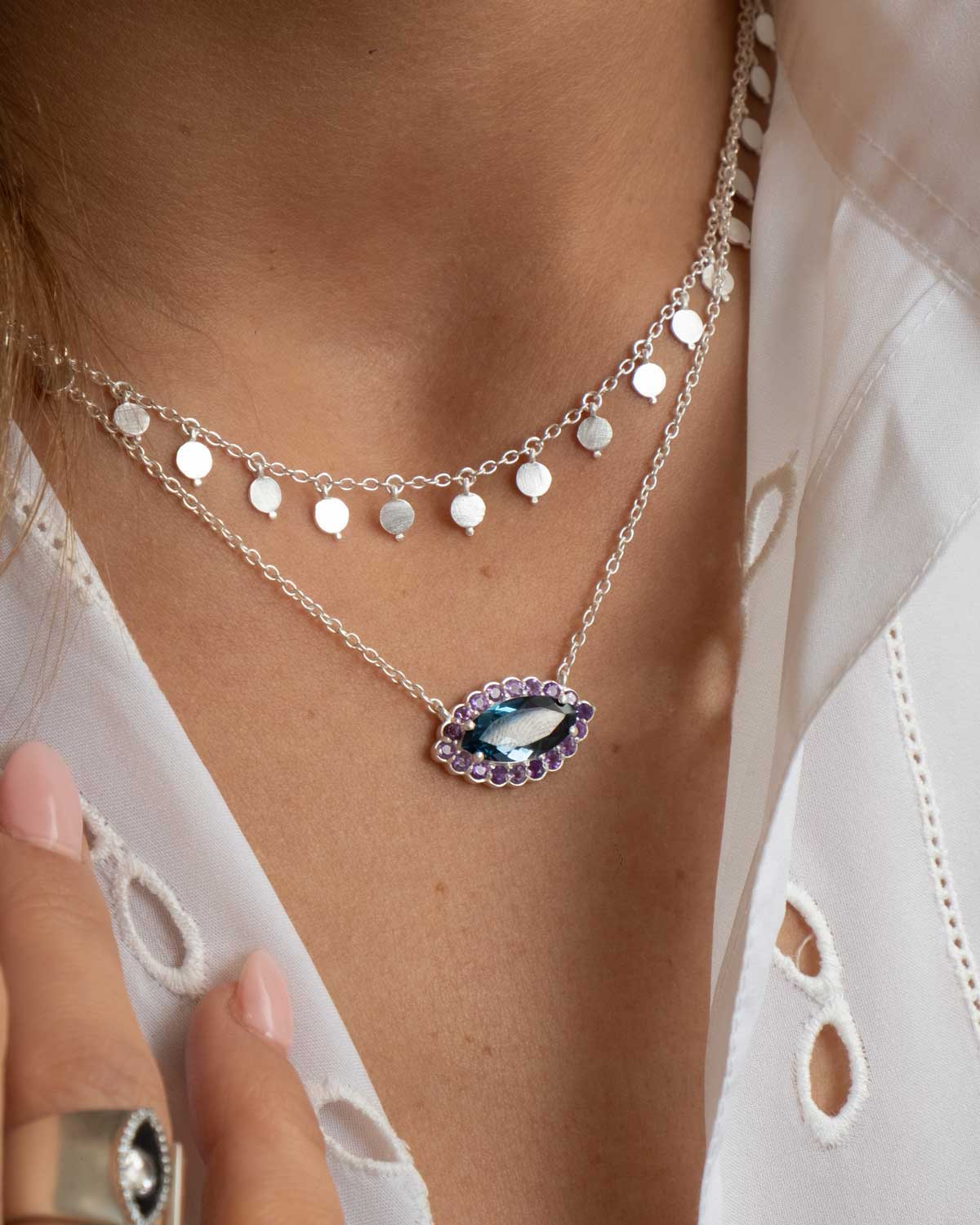 Close-up of silver eye necklace with turquoise gems and rainbow moonstone