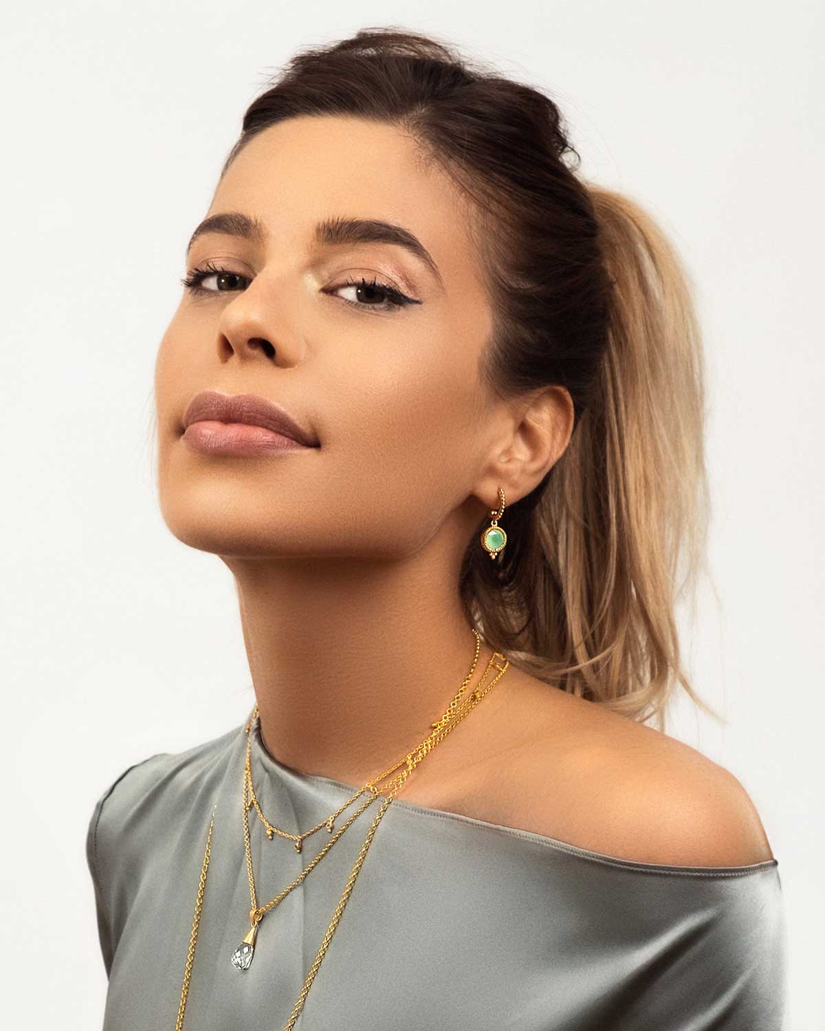 Model wearing gold mini hoops with aqua chalcedony gemstones