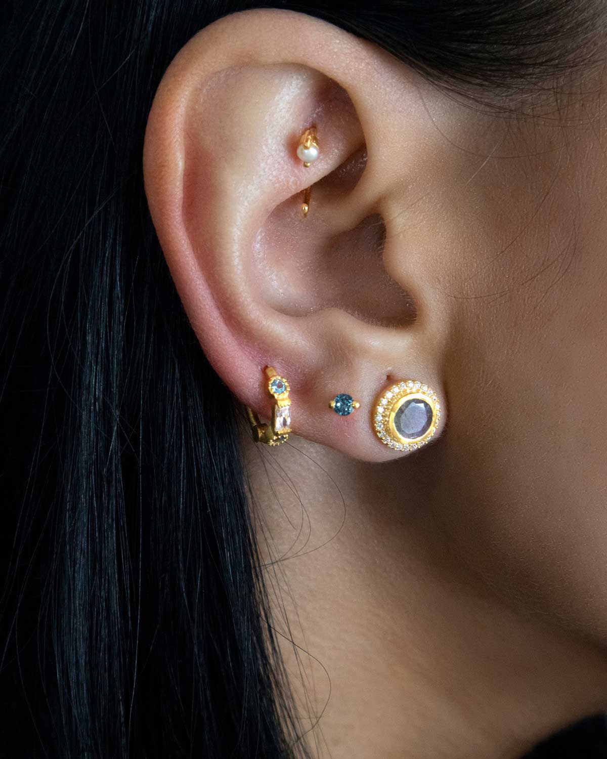 Close-up of gold mini hoops with blue topaz and cubic zirconia stones