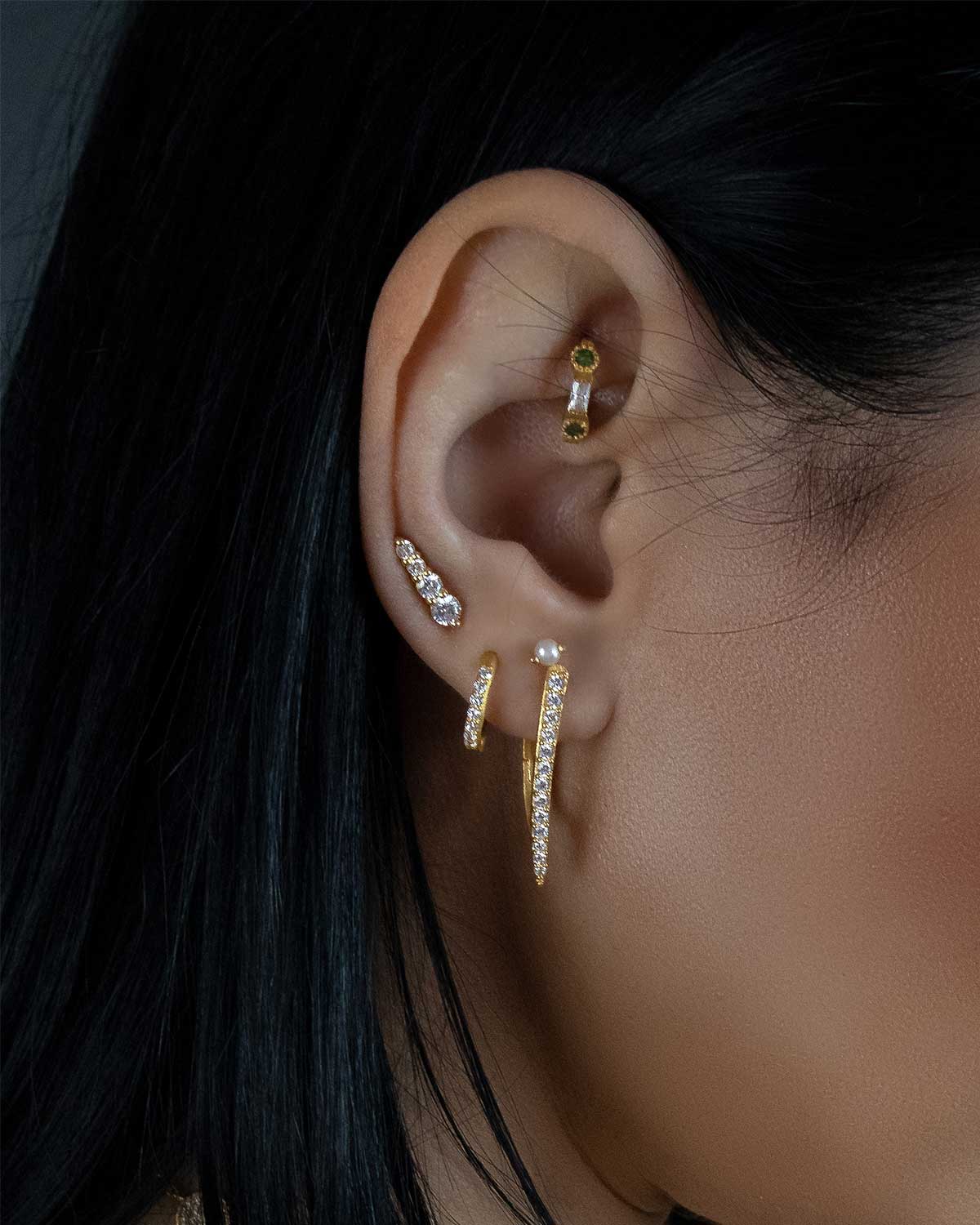 Model wearing gold mini hoop earrings with blue topaz stones