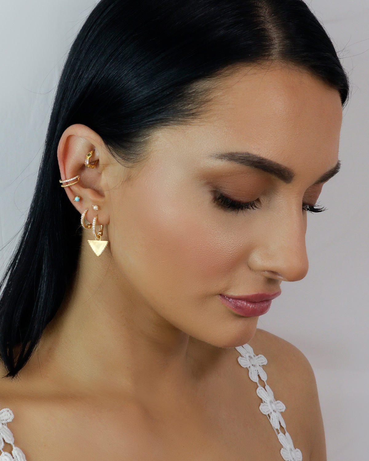 Mini pearl gold studs styled with other earrings for a modern look