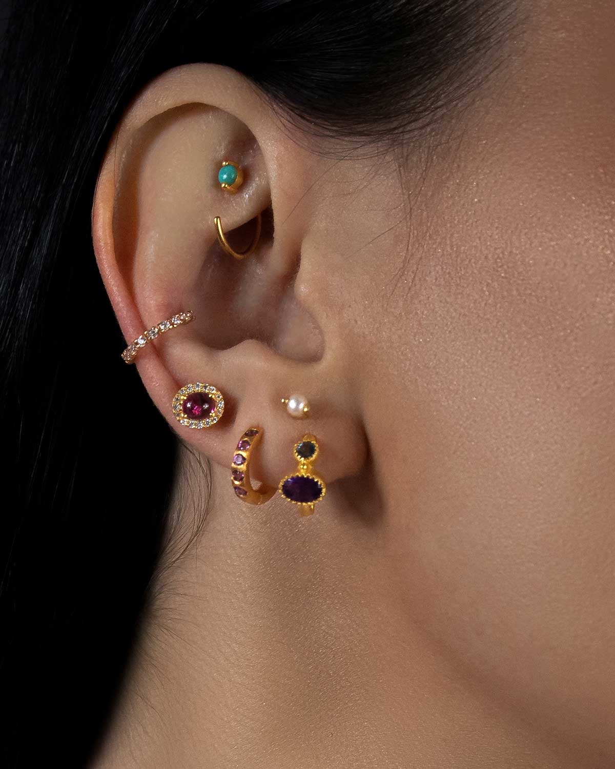Close-up of gold mini hoops with garnet and aqua calcedony gemstones