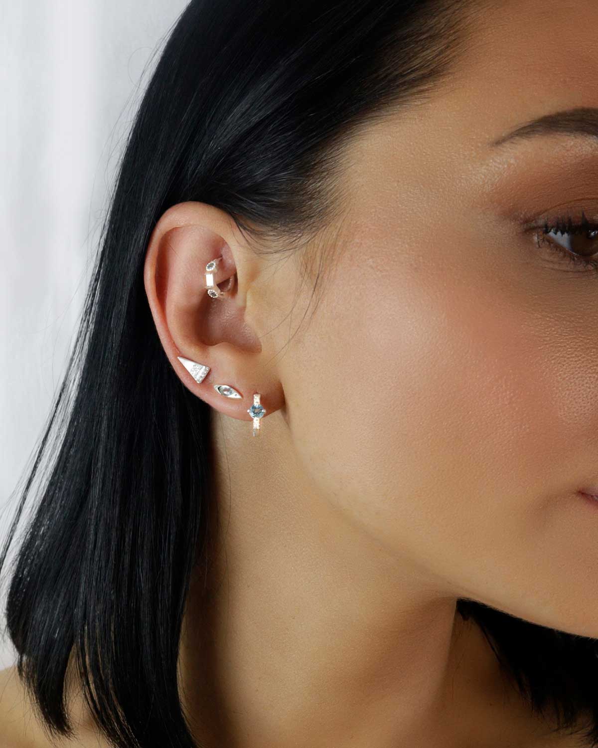 Close-up of mini gold hoops with blue topaz stones and pearls