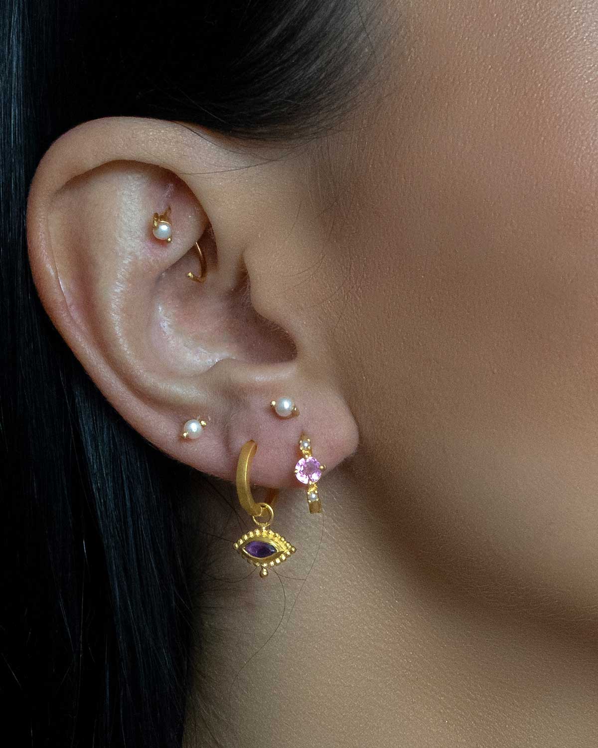 Close-up of gold mini hoops with pink tourmaline stones and organic pearls