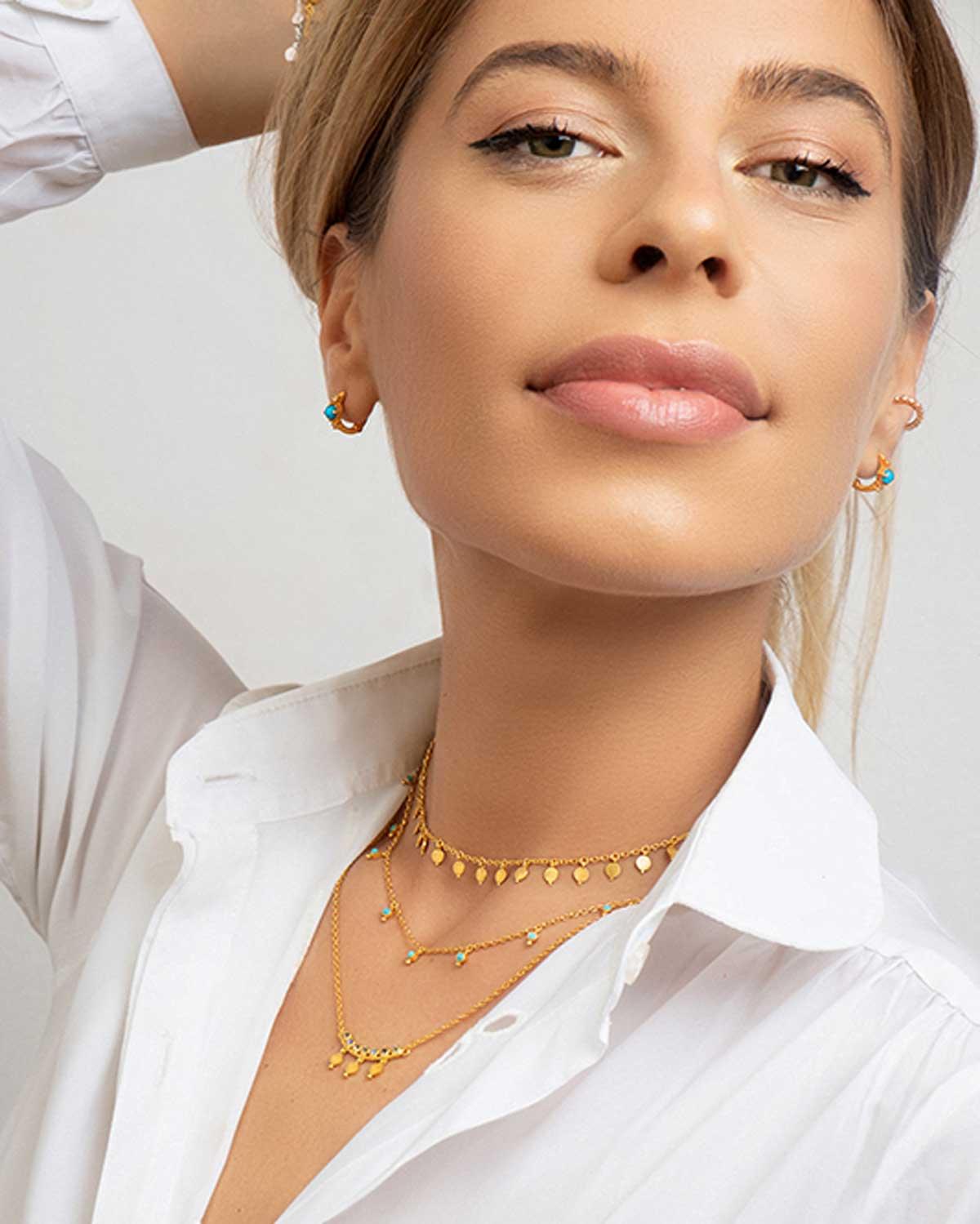 Model wearing a gold necklace with tiny amethyst gemstones