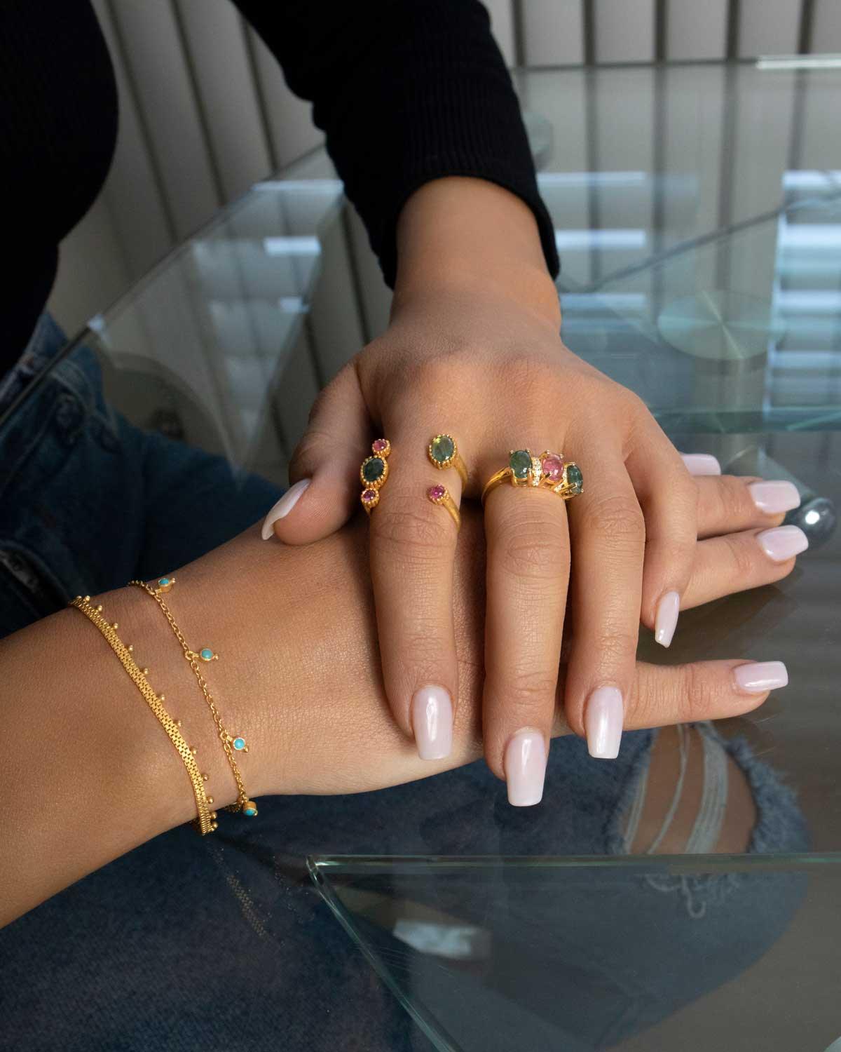 Model wearing gold bracelet with green onyx gemstone charms