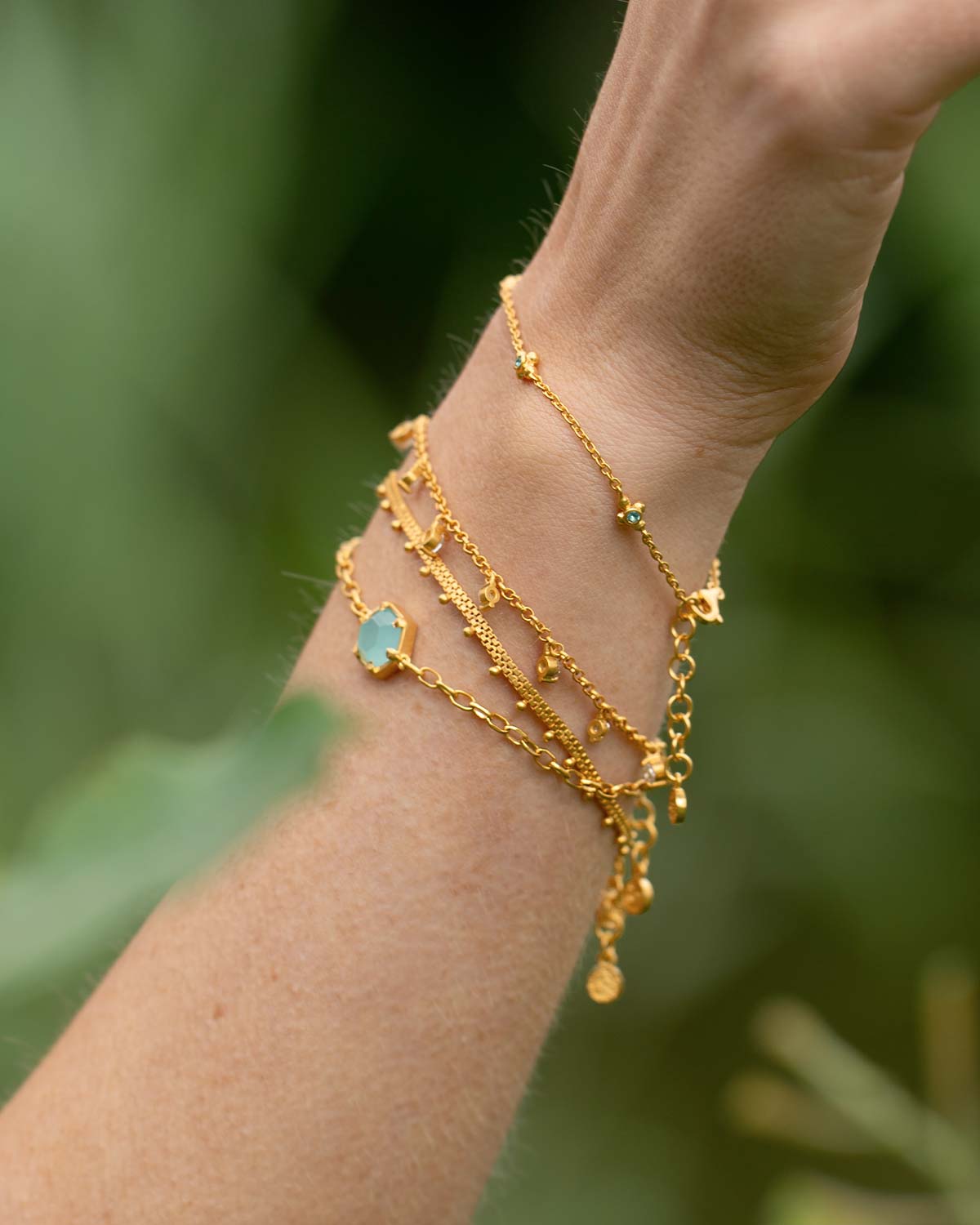 Model wearing a gold adjustable bracelet with an aqua chalcedony gemstone