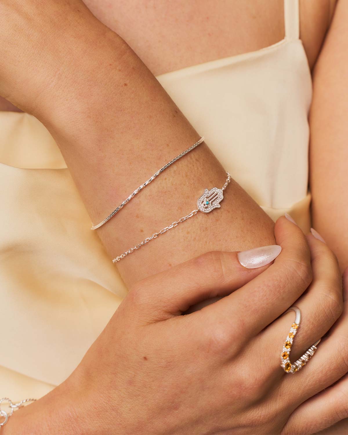 Close-up of sterling silver bracelet with hand charm, lab diamonds, and turquoise detail