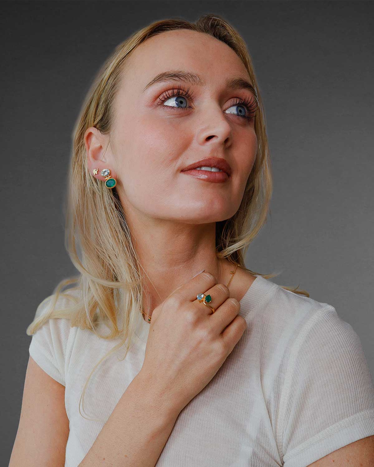 Model wearing gold earrings with blue topaz and green onyx gemstones, lightweight and handcrafted with polished finish