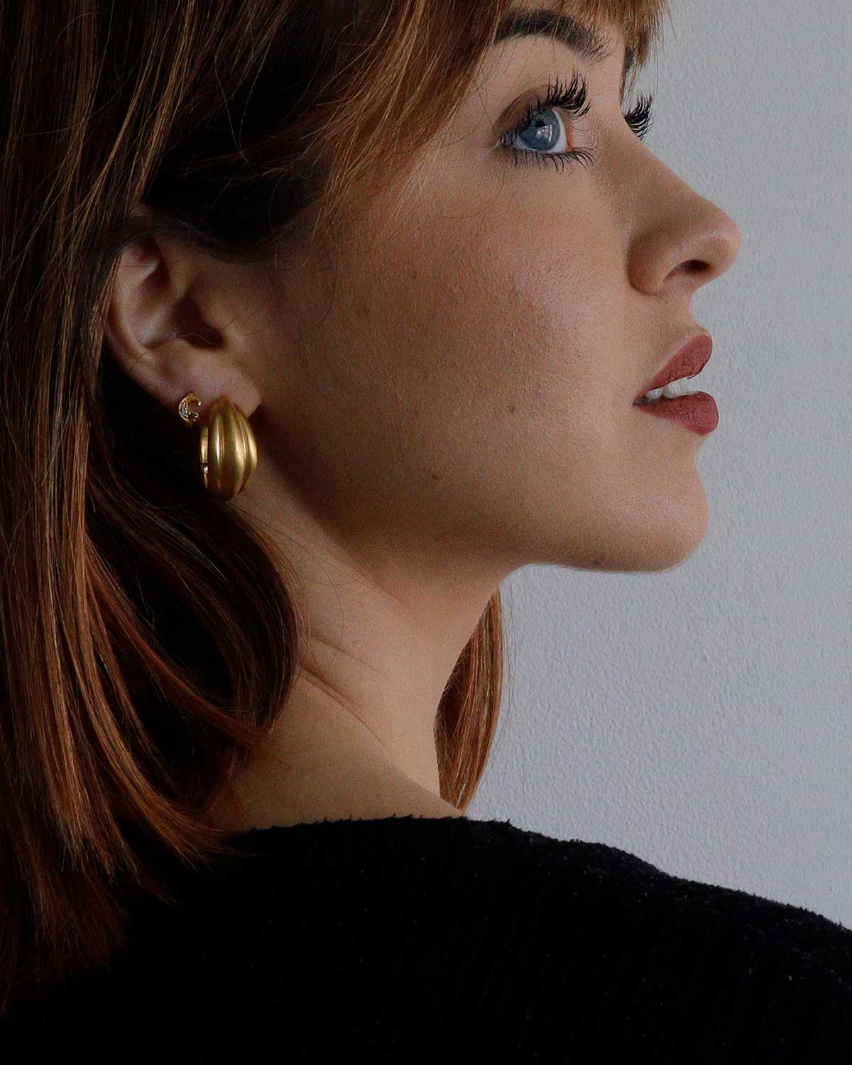 Model wearing chunky gold hoop earrings with a bold statement look