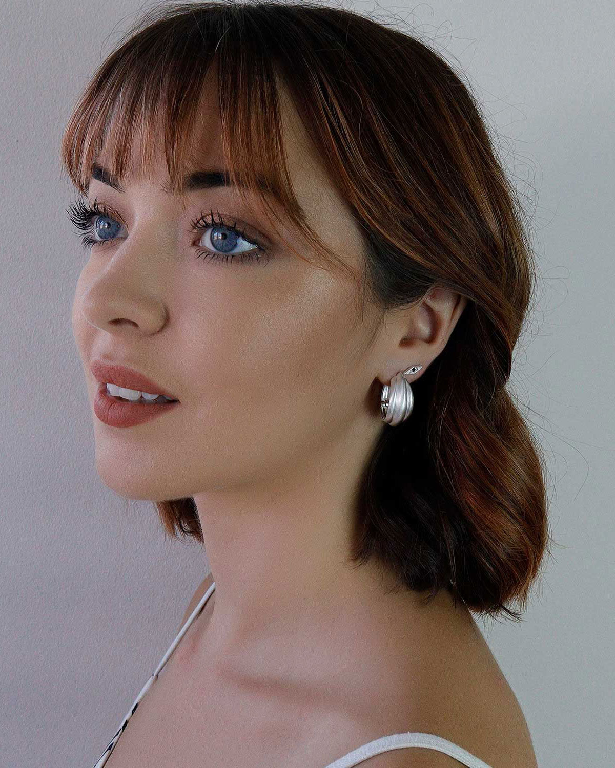 Model wearing chunky silver hoop earrings with a bold minimal style