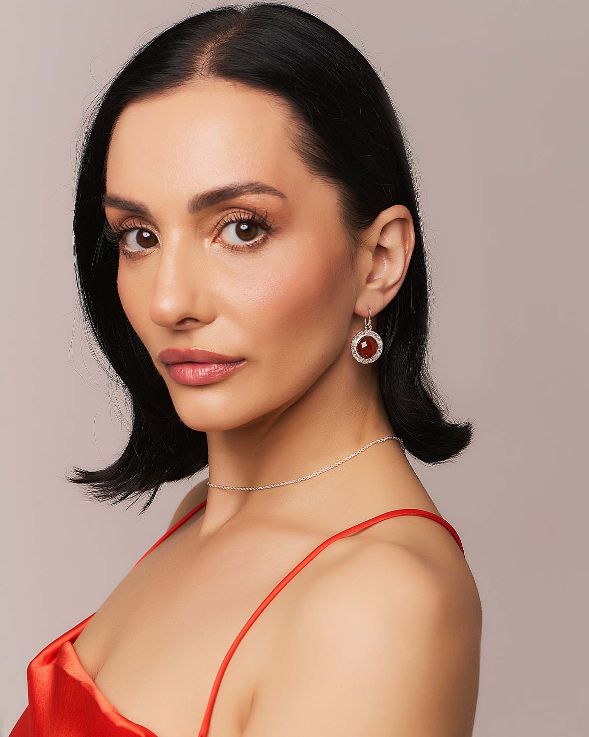 Model wearing bold gold earrings with circular carnelian gemstones