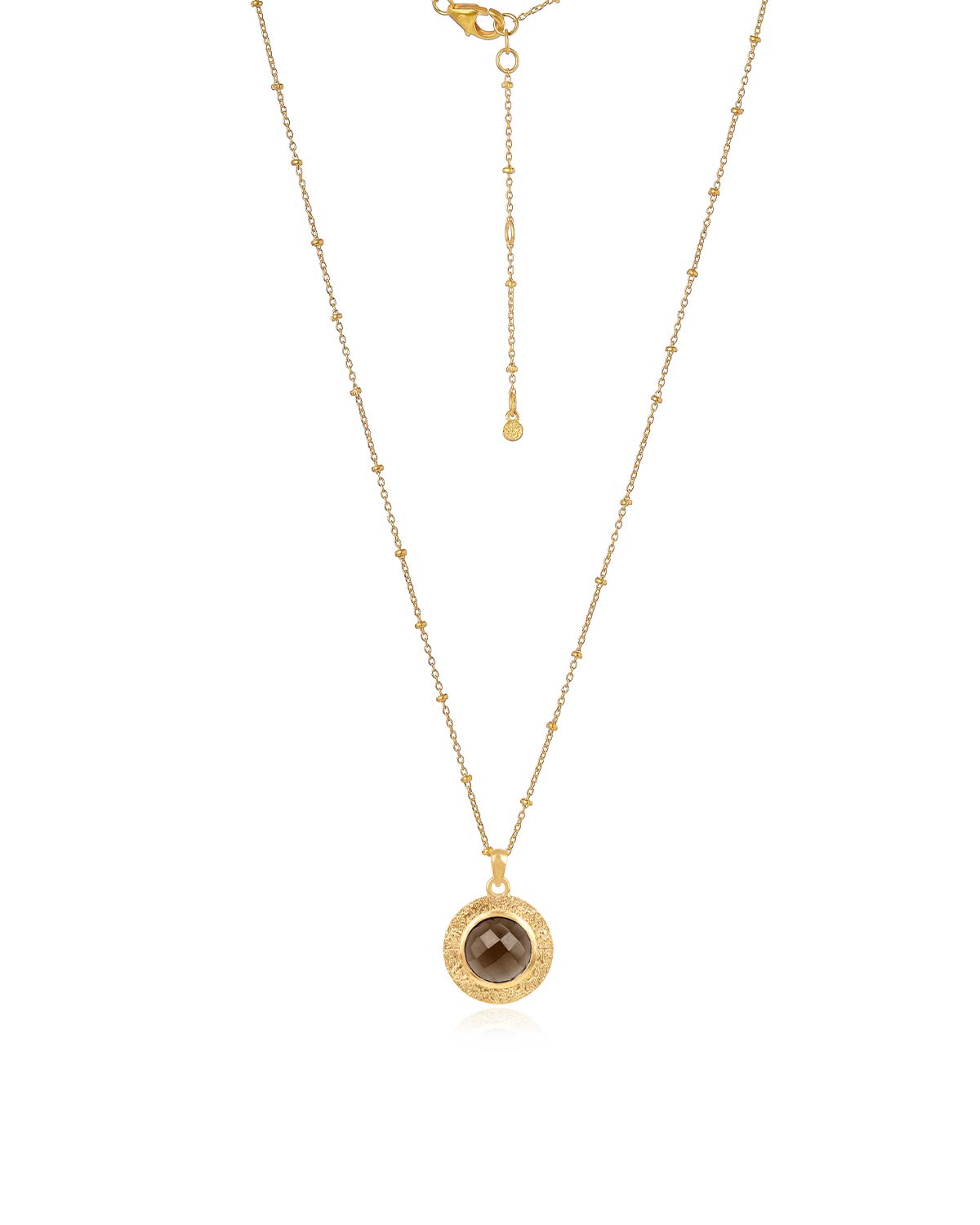 Bold gold necklace with a circular smoky quartz pendant worn as a statement piece
