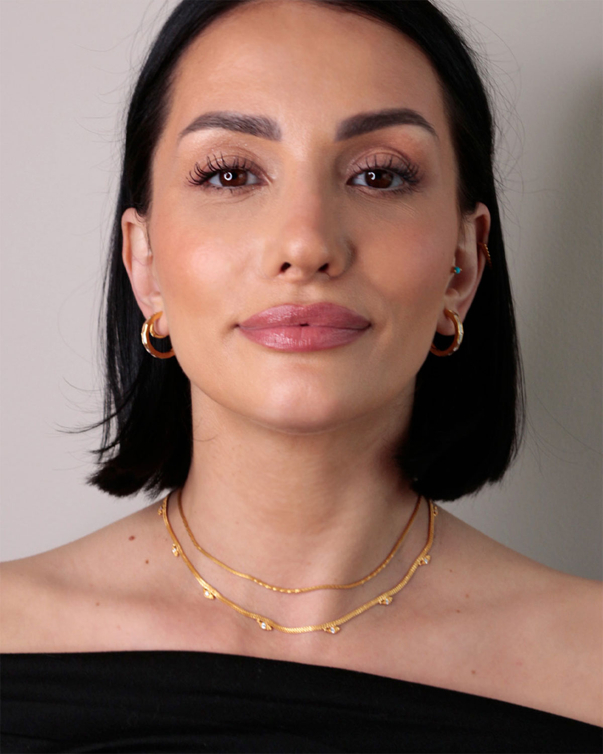 Model wearing gold midsize hoop earrings with baguette cubic zirconia stones