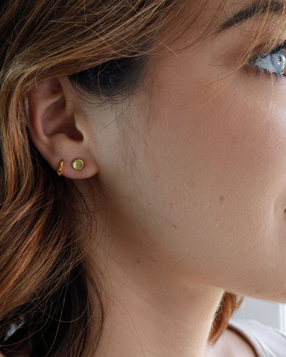 Side angle of peridot stud earrings with polished finish