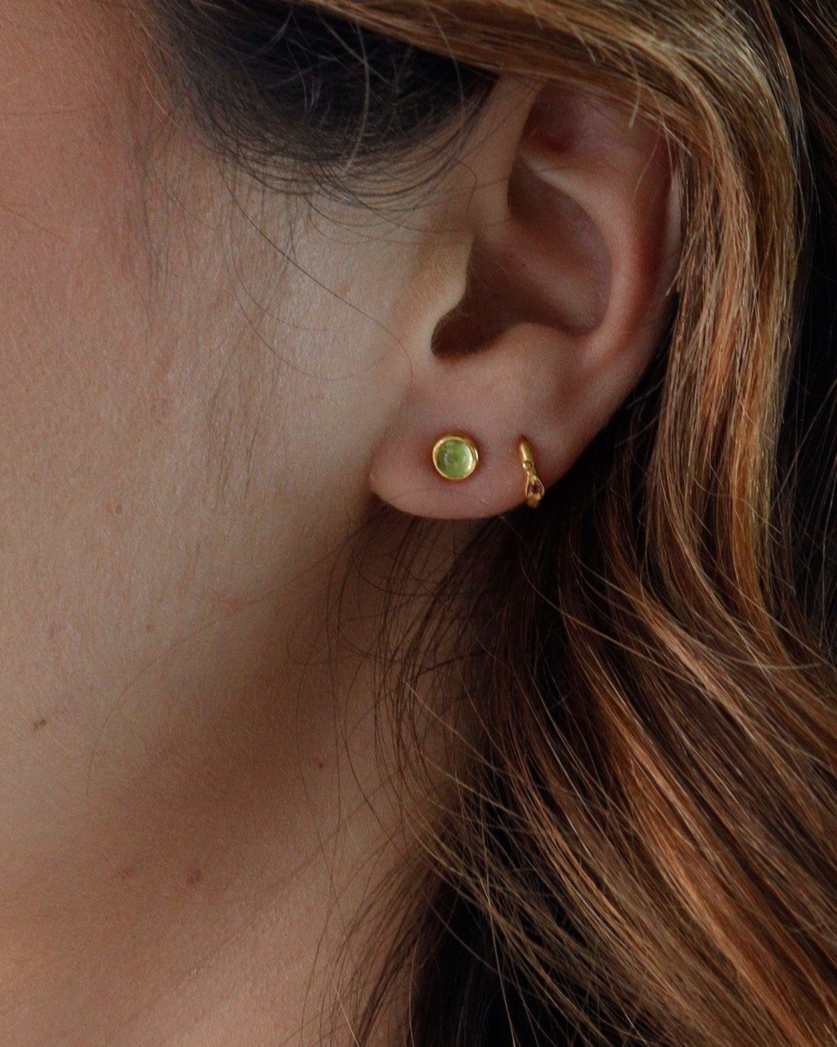 Peridot stud earrings styled in a stacking look