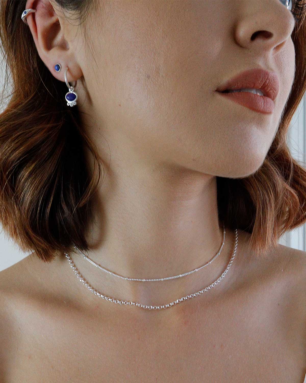 Front view of silver mini hoop earrings with lapis lazuli gemstone drop