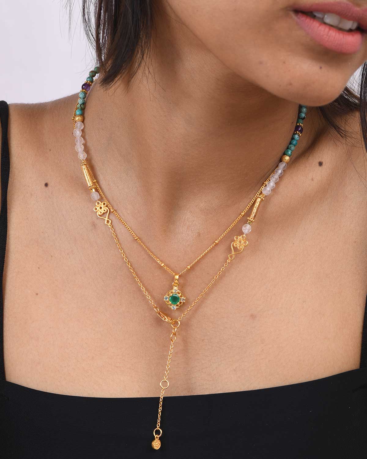 Close-up of gold necklace featuring green onyx and blue topaz gemstones
