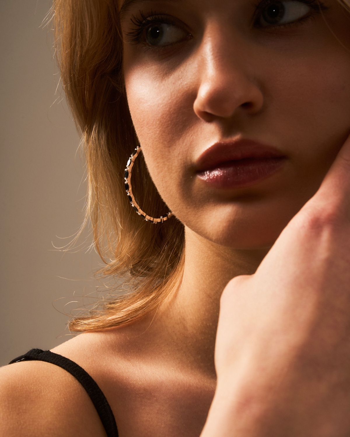 Angled view of gold vermeil hoop earrings with black spinel gemstone detailing