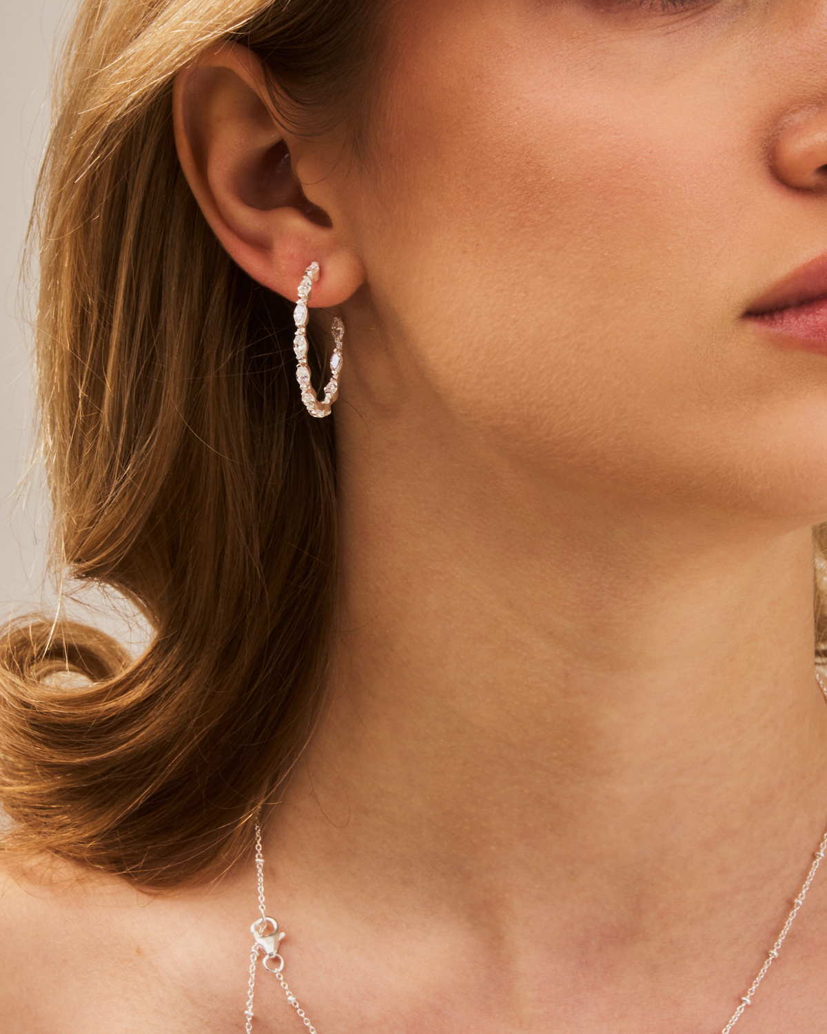 Model wearing sparkling silver hoop earrings with marquise-cut zirconia stones