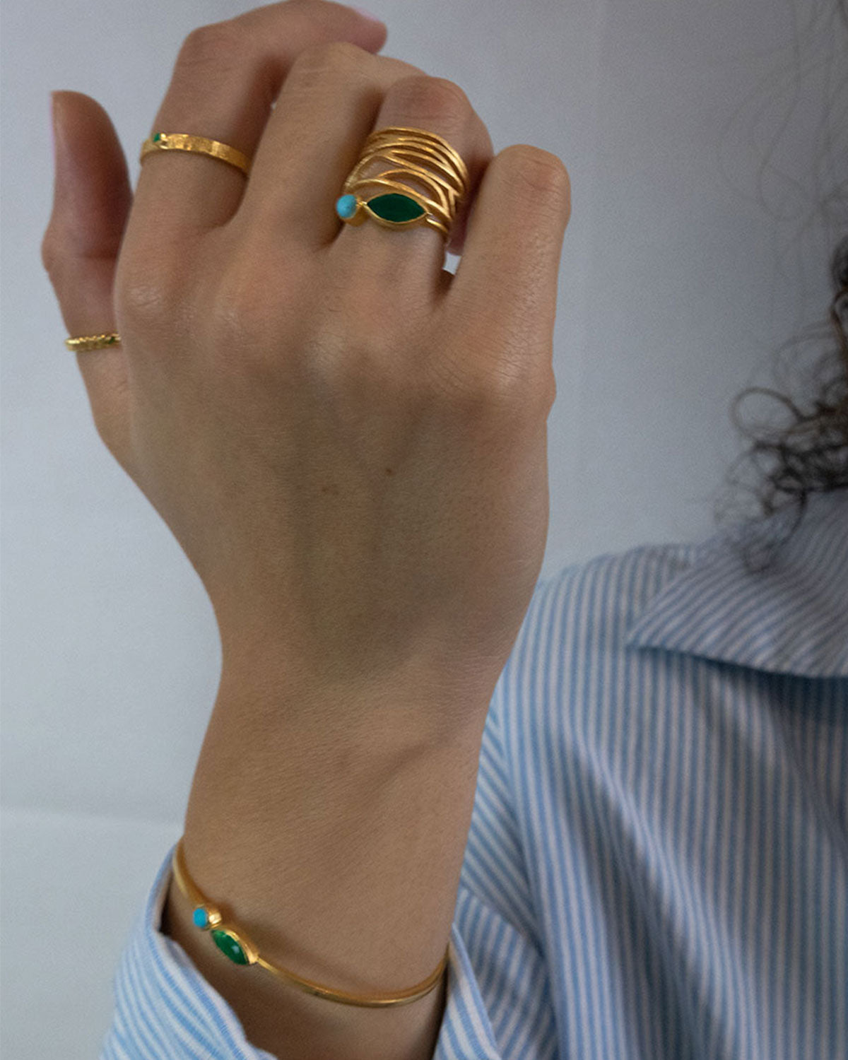 Close-up of gold rings featuring green onyx and turquoise gemstones