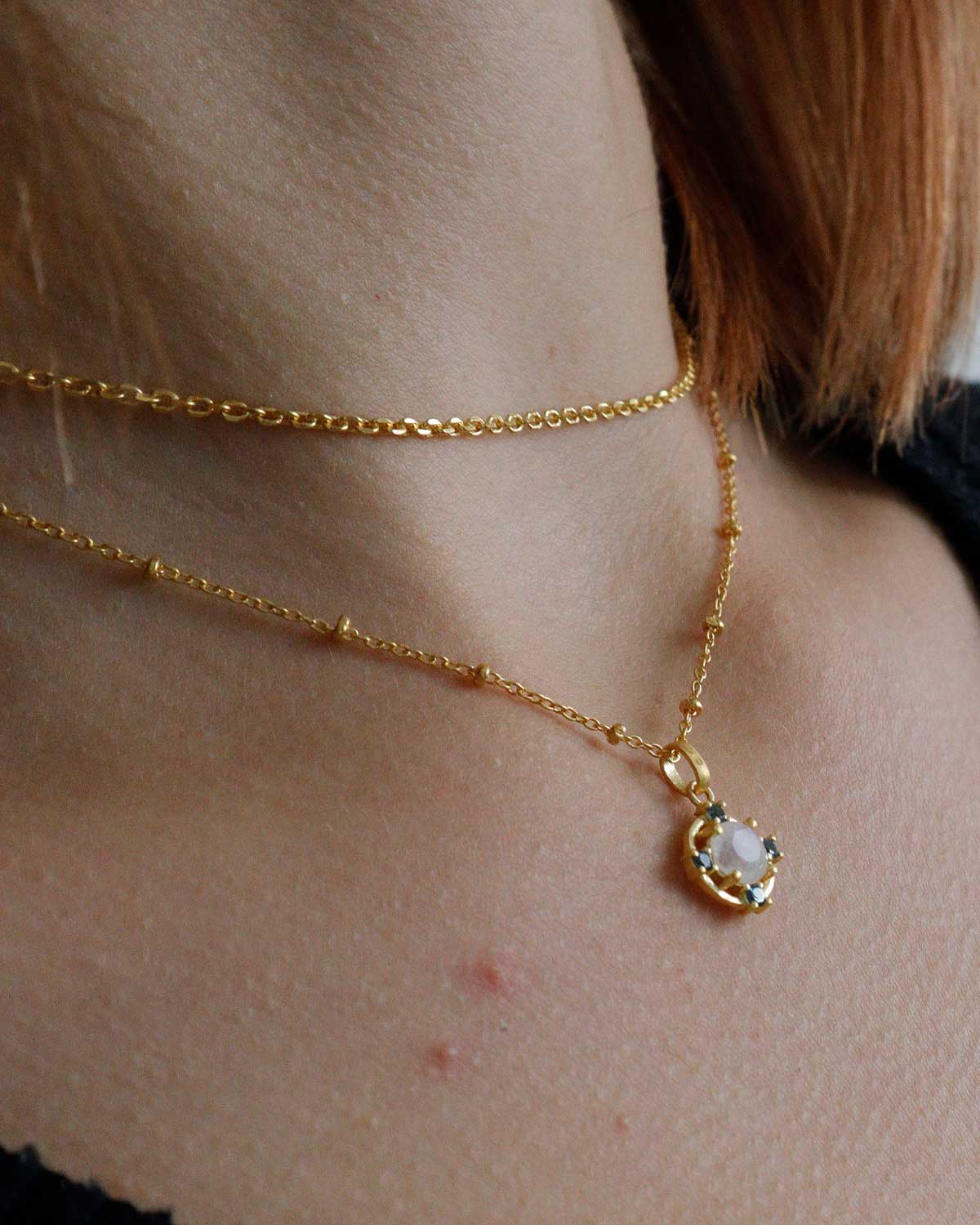 Close-up of gold necklace with moonstone and blue topaz gemstones