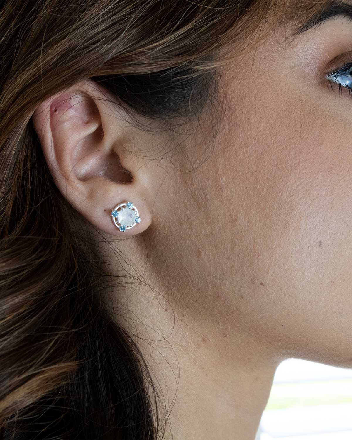 Close-up of silver stud earrings with moonstone and blue topaz crystals