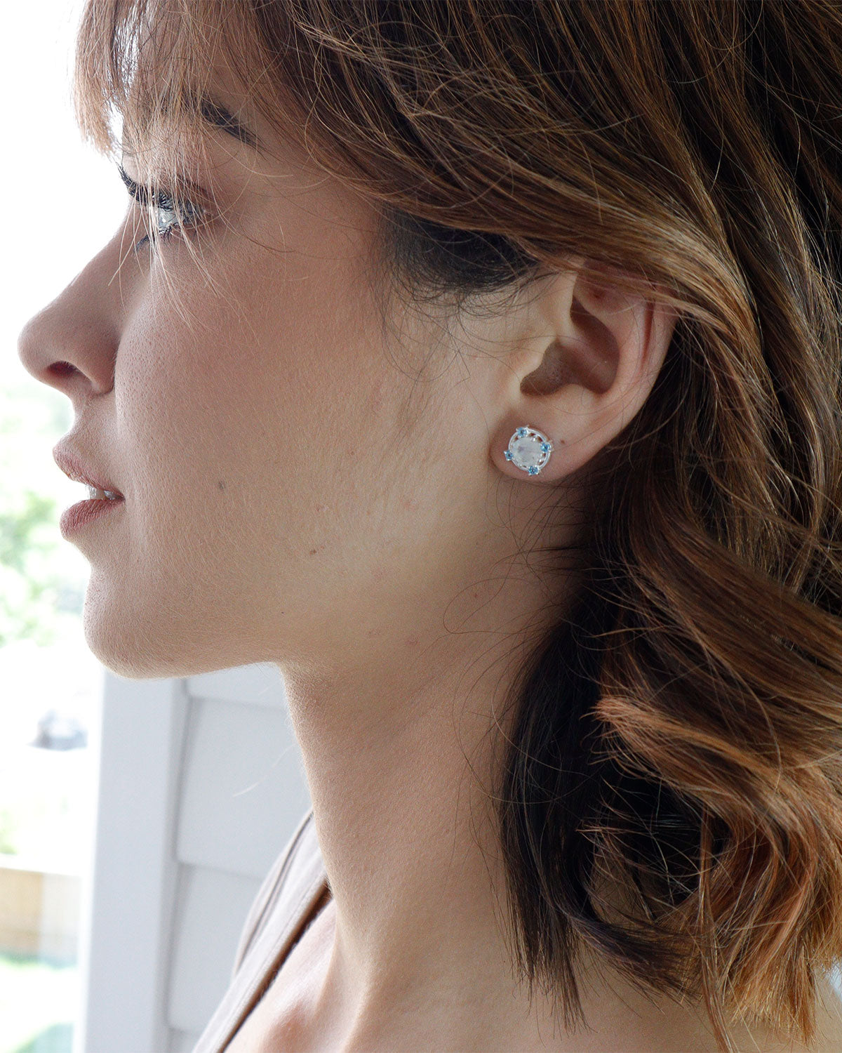 Side angle of sterling silver earrings featuring moonstone and blue topaz