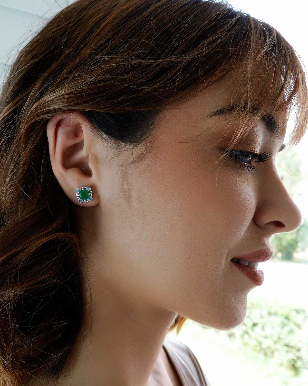 Close-up of silver stud earrings with green onyx and blue topaz
