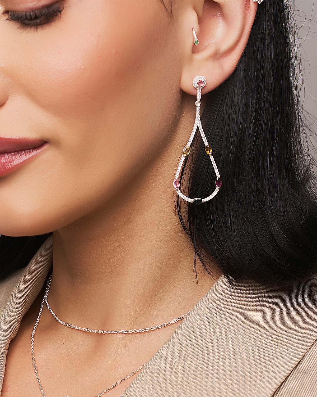 Close-up of silver drop earrings showcasing colorful tourmaline gemstones and cubic accents