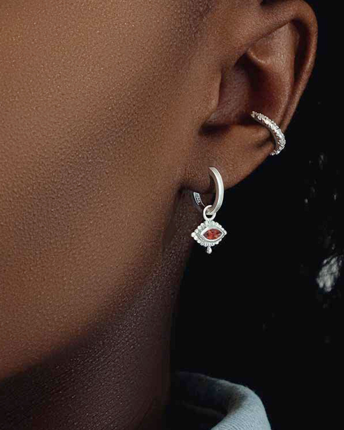 Model wearing gold mini hoops with eye design and amethyst gemstone charm