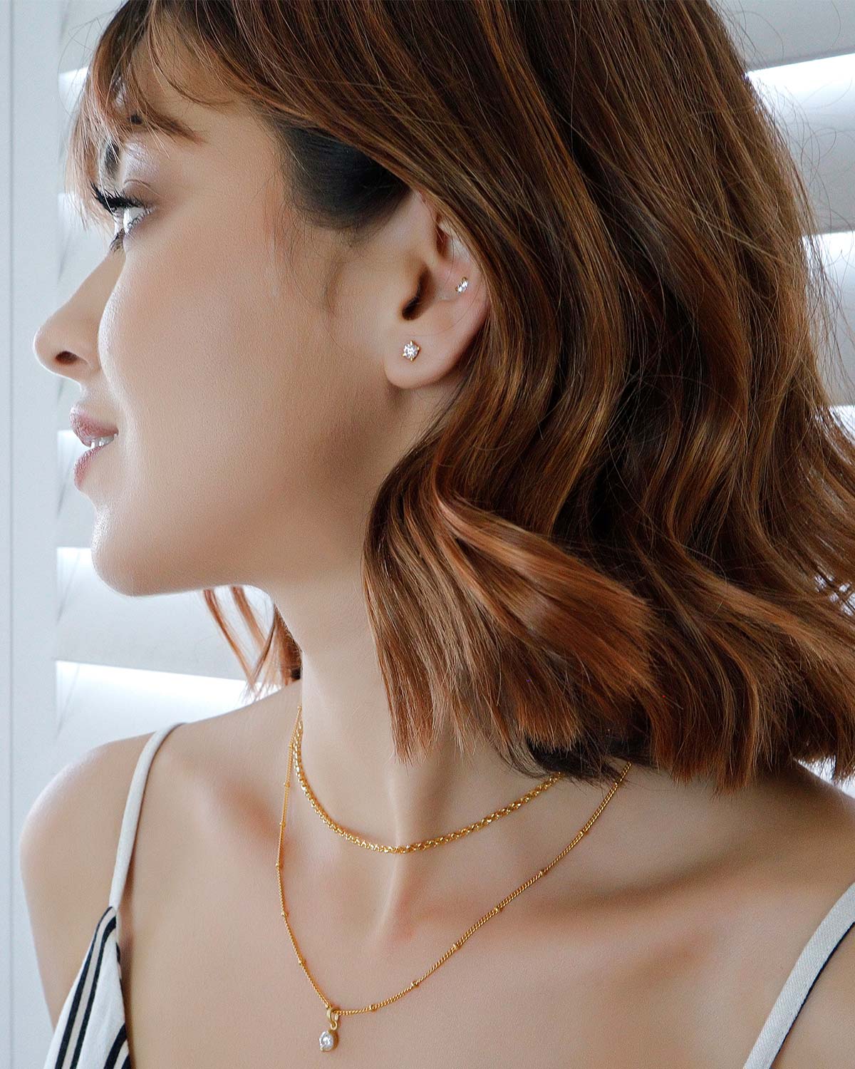 Model wearing gold stud earrings with white moissanite diamonds
