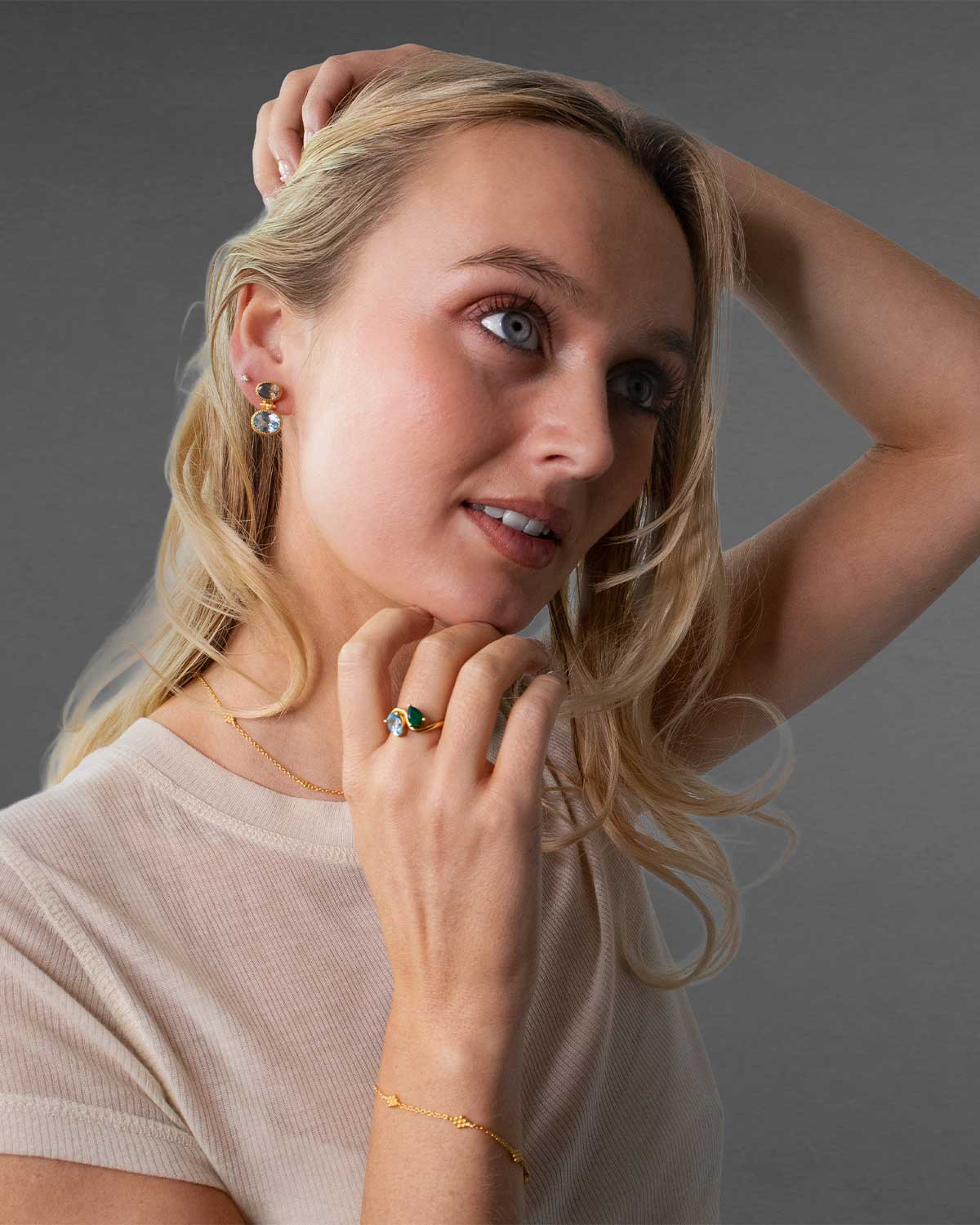 Angled view of gold ring showcasing pear-shaped blue topaz and green onyx gemstones