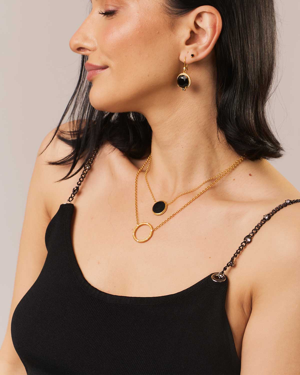 Model wearing gold earrings with black spinel and labradorite gemstones