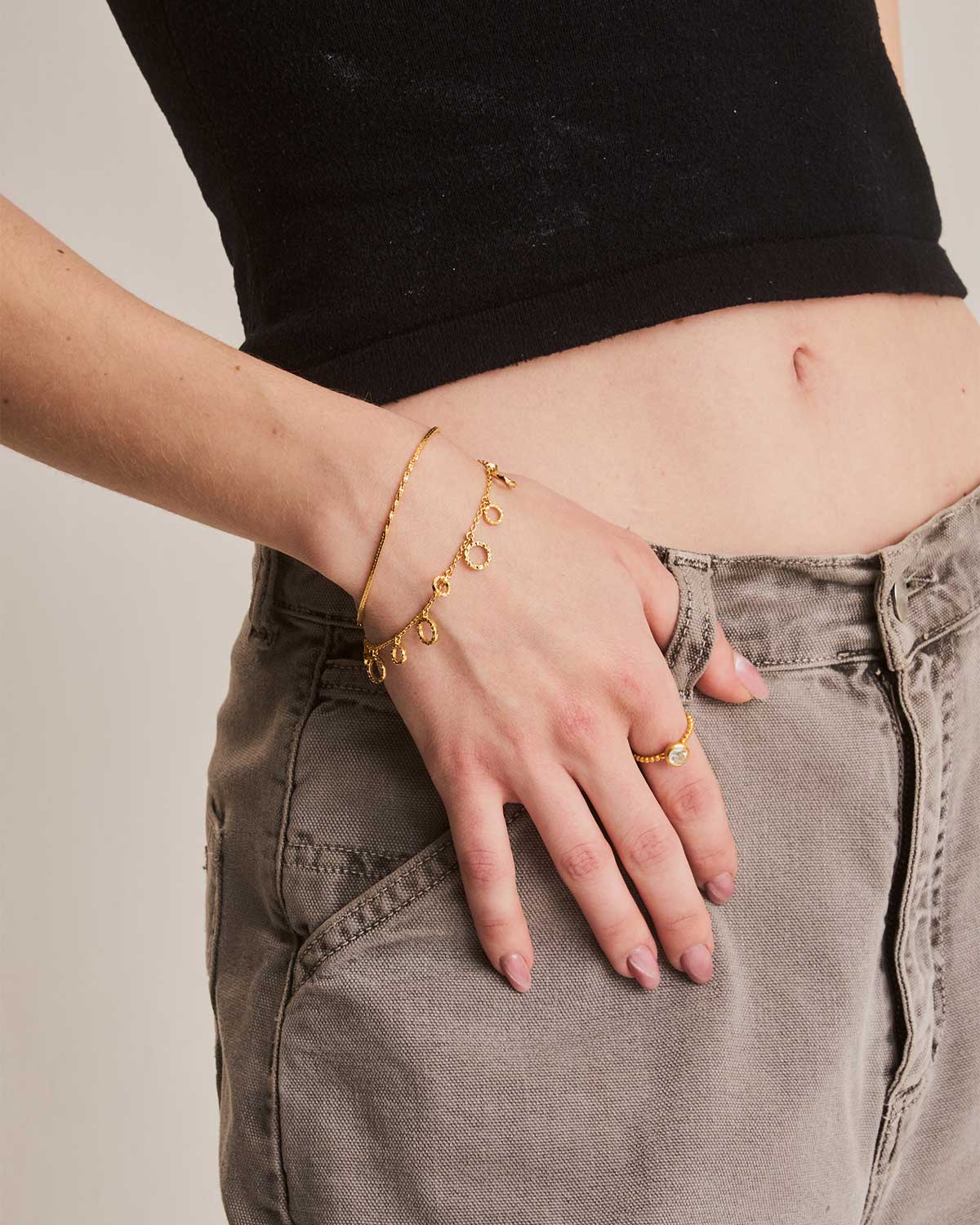 Model wearing gold bracelet with a hammered round disc