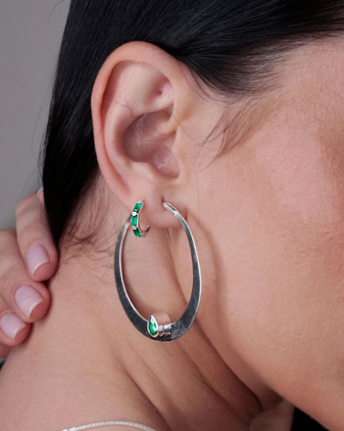 Close-up of large silver hoop earrings with green onyx gemstones