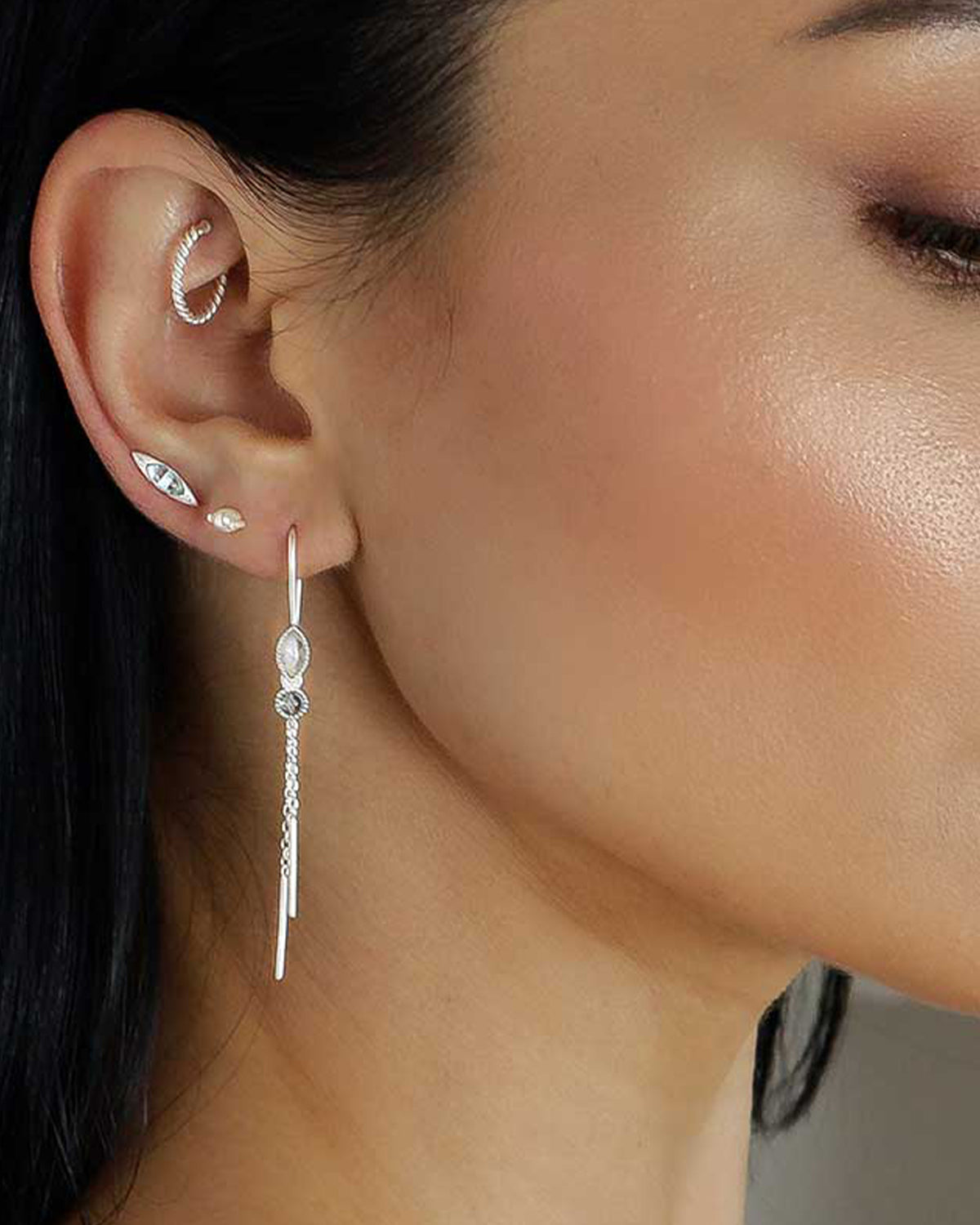 Close-up of silver drop earrings with turquoise and pearl gemstones