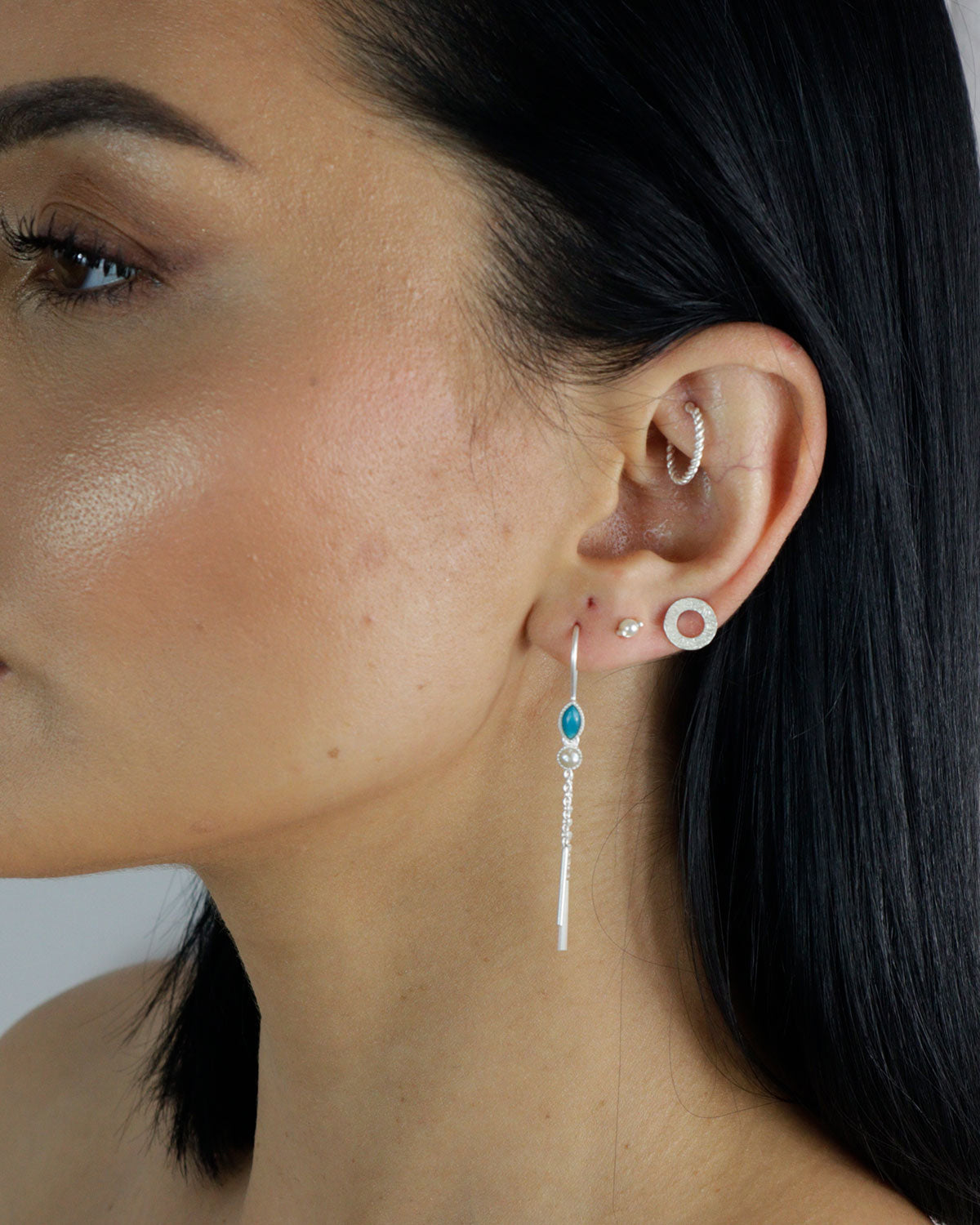 Model wearing silver drop earrings with mixed gemstones