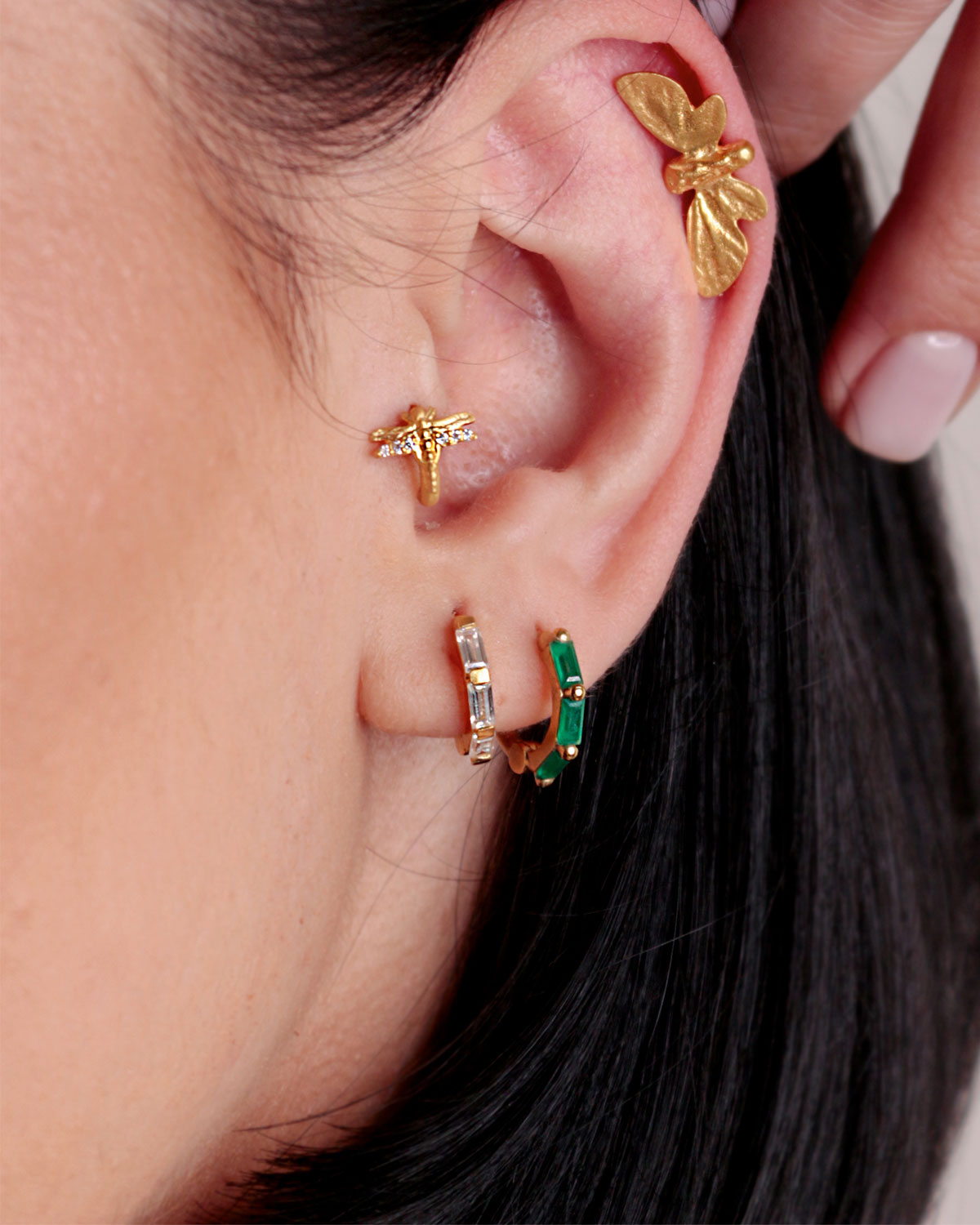 Model wearing gold mini hoop earrings with emerald green onyx gemstones
