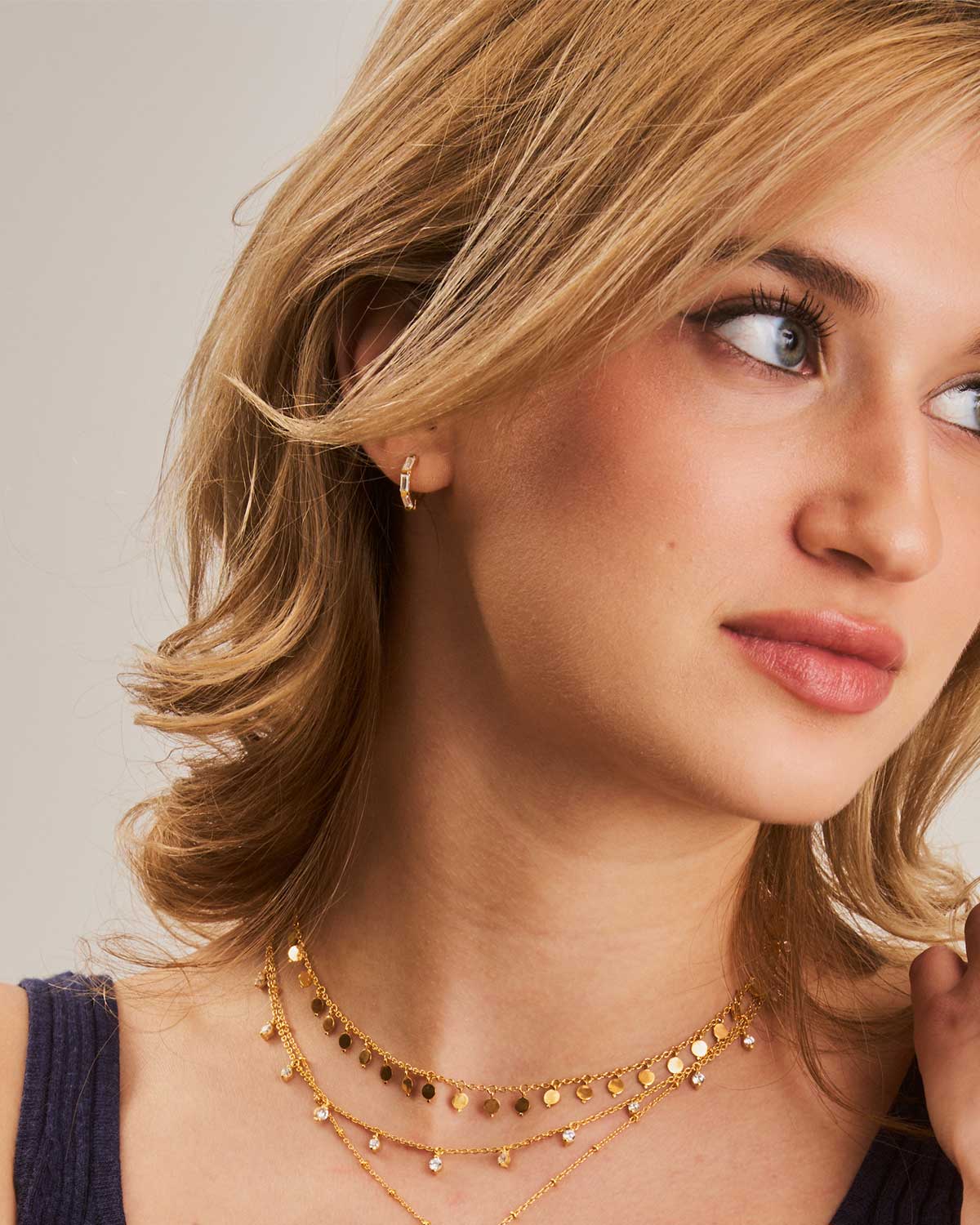 Model wearing gold mini hoop earrings with baguette cubic zirconia
