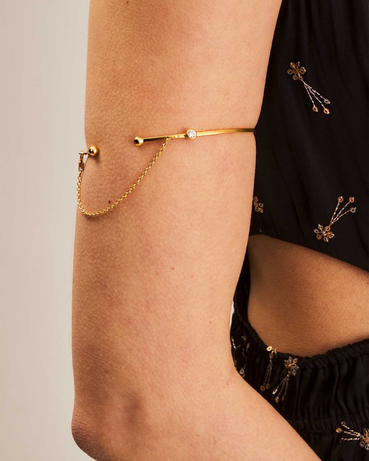 Side view of gold arm cuff highlighting gemstones